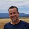 Andrew Oliphant standing in front of a meadow, headshot