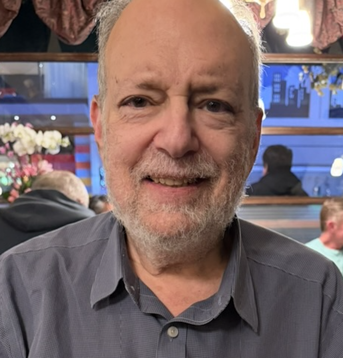 Headshot of man smiling at camera wearing grey shirt