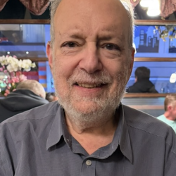Headshot of man smiling at camera wearing grey shirt